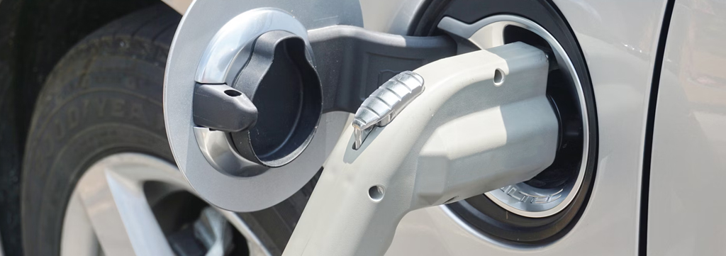 Close up image of white EV vehicle plugged in